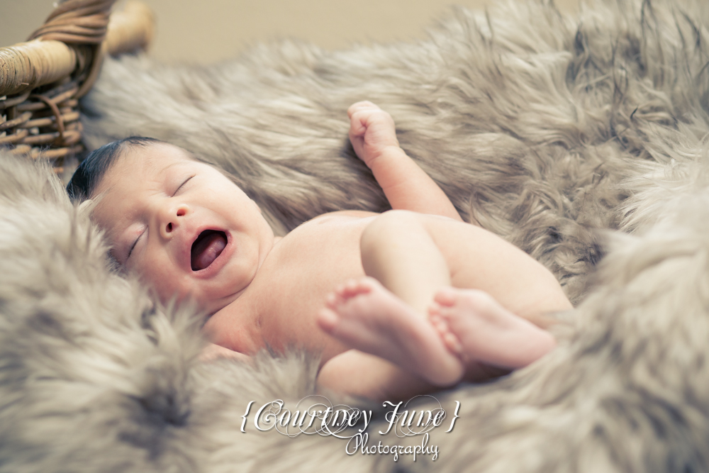 newborn photographer photographing a newborn laughing in a furry rug 