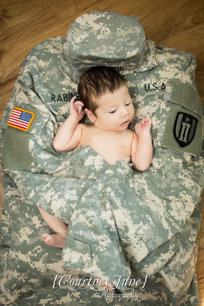 newborn photographer photographing a newborn laying on daddy's army jacket 