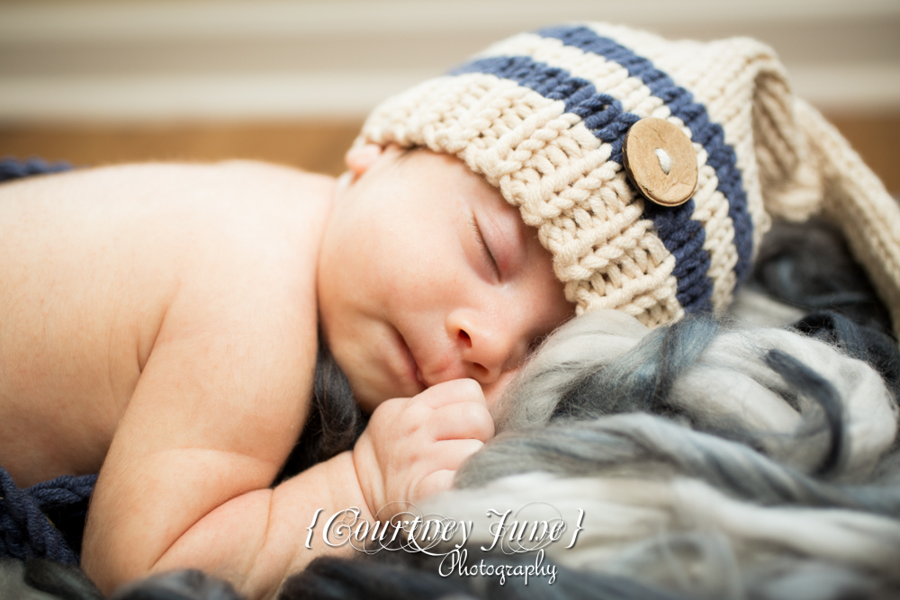 newborn photographer photographing a closeup of a newborn with a knit hat on 
