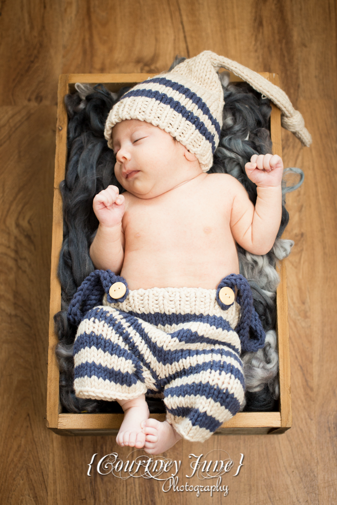 newborn photographer photographing a newborn in a wooden crate with a knit outfit and knit hat